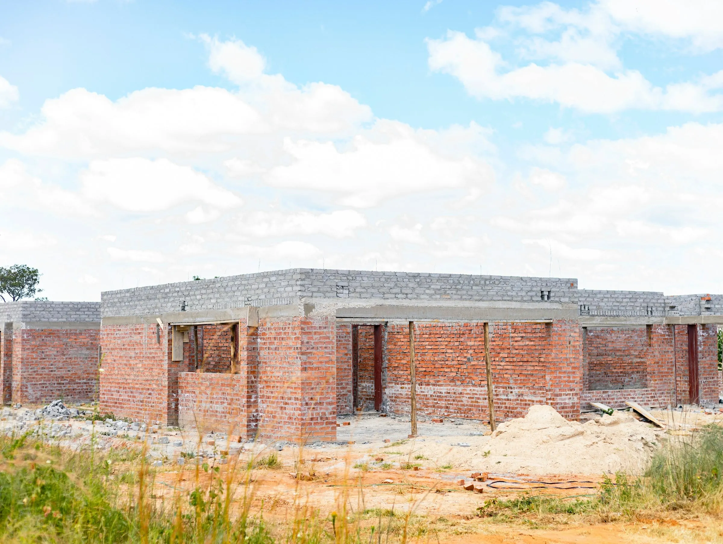 House under construction with red brick walls and concrete roof